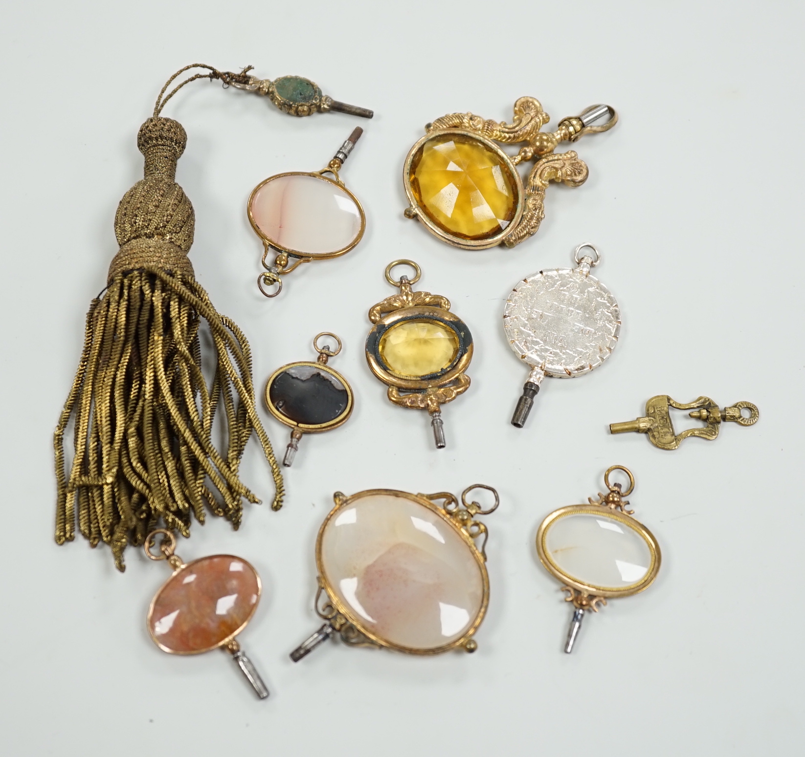 Ten assorted mainly 19th century base or yellow metal oval and gem set large watch keys, including agate and citrine paste and one set with French medallion, largest 69mm.